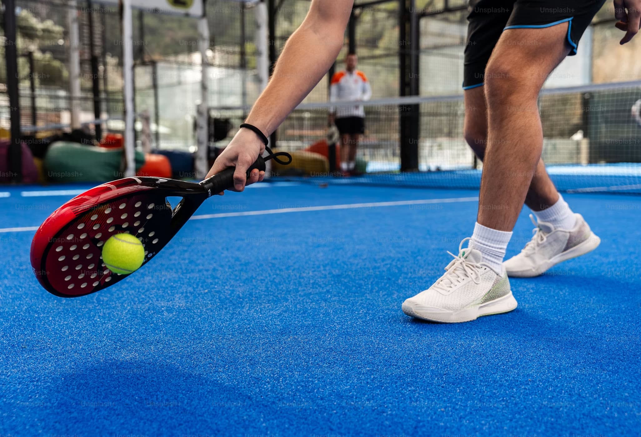 Padel player about to strike the ball on a blue court