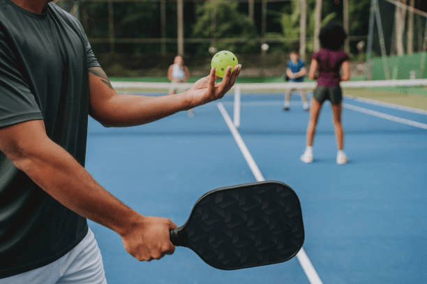 Pickleball player serving on an outdoor blue court